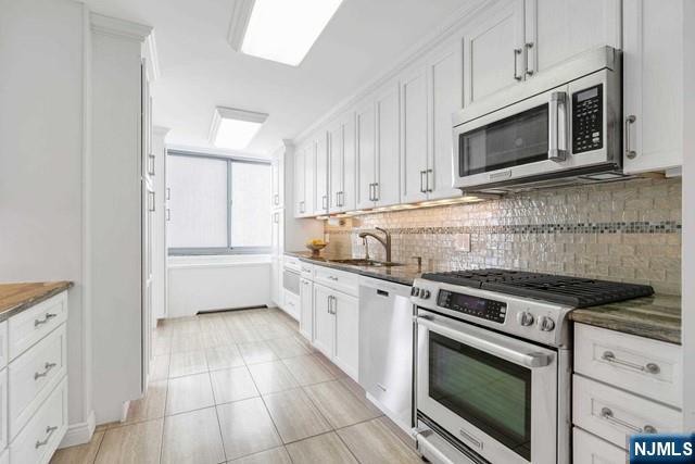 1600 Parker Ave Unit 1G, Fort Lee, NJ 07024 - kitchen featuring appliances with stainless steel finishes, backsplash, white cabinets, and light tile patterned floors
