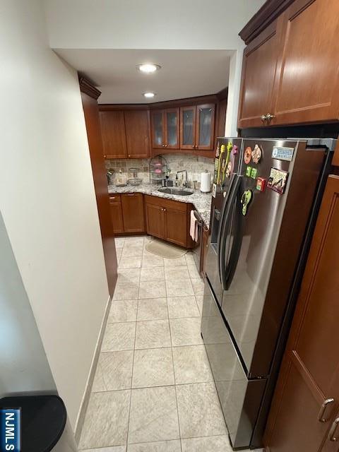 900 Palisade Unit 1-J, Fort Lee, NJ 07024 - kitchen with stainless steel refrigerator with ice dispenser, light tile patterned floors, tasteful backsplash, light stone counters, and glass insert cabinets