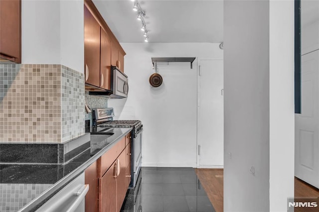 500 Linwood Dr Unit 5H, Fort Lee, NJ 07024 - kitchen with appliances with stainless steel finishes, tasteful backsplash, dark countertops, brown cabinetry, and dark tile patterned floors