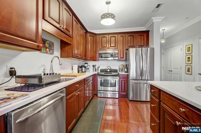 20 Ave At Port Imperial 425, West New York, NJ 07093 - kitchen featuring stainless steel appliances, light countertops, dark wood-style floors, decorative light fixtures, and ornamental molding