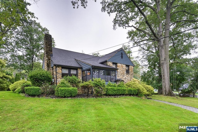 99 Chestnut Dr, Wayne, NJ 07470 - view of front facade featuring stone siding, a front yard, a sunroom, a chimney, and a shingled roof