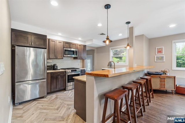 37 Golf Ct, Teaneck, NJ 07666 - kitchen with stainless steel appliances, dark brown cabinetry, a breakfast bar, decorative backsplash, and recessed lighting