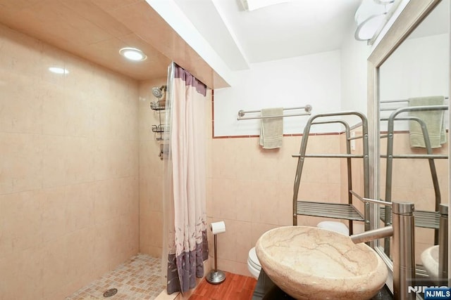 116 Sherman Ave, Teaneck, NJ 07666 - bathroom featuring tiled shower, tile walls, wood finished floors, and a wainscoted wall