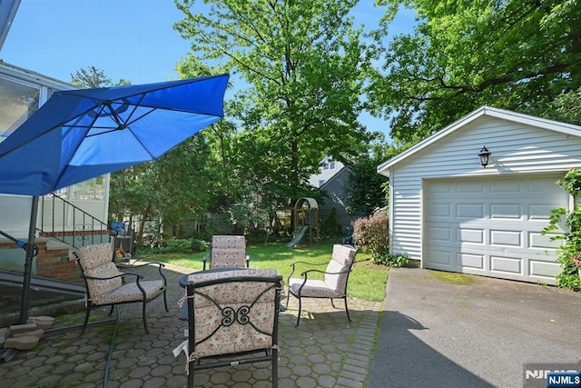 116 Sherman Ave, Teaneck, NJ 07666 - view of patio with a detached garage, a playground, asphalt driveway, and an outdoor structure