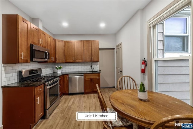 87 James St, Englewood, NJ 07631 - kitchen with stainless steel appliances, light wood-style flooring, backsplash, brown cabinetry, and dark stone countertops