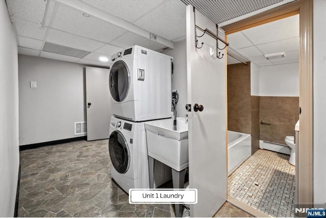 87 James St, Englewood, NJ 07631 - laundry area with stacked washer and clothes dryer, stone finish floors, and a baseboard heating unit