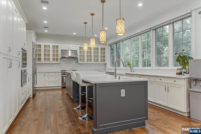 8 Oratam Rd, Upper Saddle River, NJ 07458 - kitchen with under cabinet range hood, white cabinetry, ornamental molding, tasteful backsplash, and dark wood-style floors