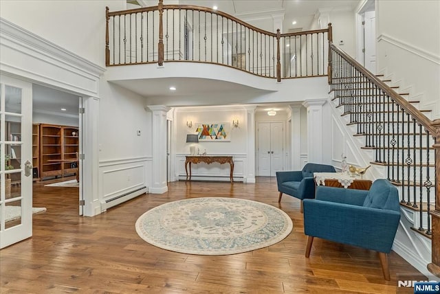 8 Oratam Rd, Upper Saddle River, NJ 07458 - living room with a baseboard radiator, ornate columns, a decorative wall, a towering ceiling, and stairway