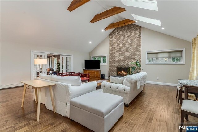 8 Oratam Rd, Upper Saddle River, NJ 07458 - living area with beamed ceiling, a skylight, high vaulted ceiling, light wood finished floors, and a brick fireplace