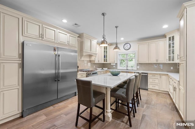 66 Andover Ter, Glen Rock, NJ 07452 - kitchen with high end appliances, cream cabinets, glass insert cabinets, a kitchen island, and recessed lighting
