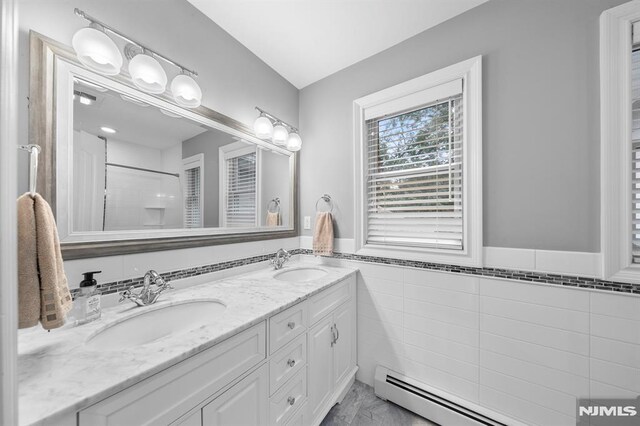66 Andover Ter, Glen Rock, NJ 07452 - full bath featuring tile walls, double vanity, a baseboard heating unit, a wainscoted wall, and a shower