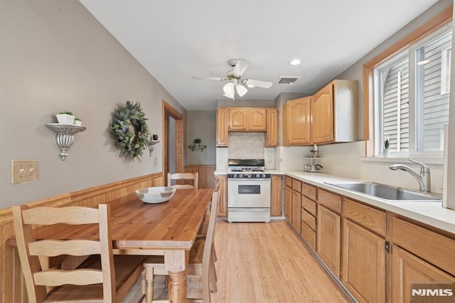350 Walnut St, Nutley, NJ 07110 - kitchen with white range with gas stovetop, a ceiling fan, light countertops, light wood-style floors, and wainscoting