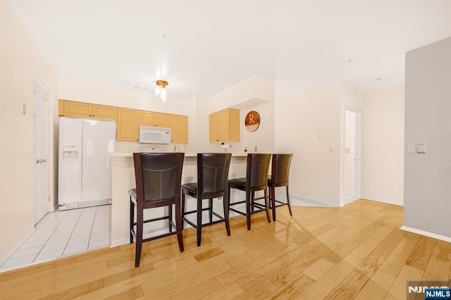 2112 Schindler Ln, Wayne, NJ 07470 - kitchen with white appliances, light wood-style floors, a kitchen bar, light countertops, and a peninsula