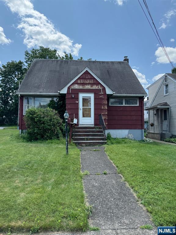 84 Miller Ave, Elmwood Park, NJ 07407 - bungalow-style home featuring a front yard, a shingled roof, entry steps, and a chimney