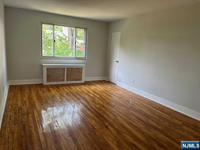 125 E Clinton Unit 10B, Bergenfield, NJ 07621 - spare room featuring radiator heating unit and wood-type flooring