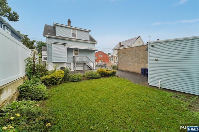 174-176 Albion Ave, Paterson, NJ 07502 - back of property with a yard, a chimney, and a shingled roof
