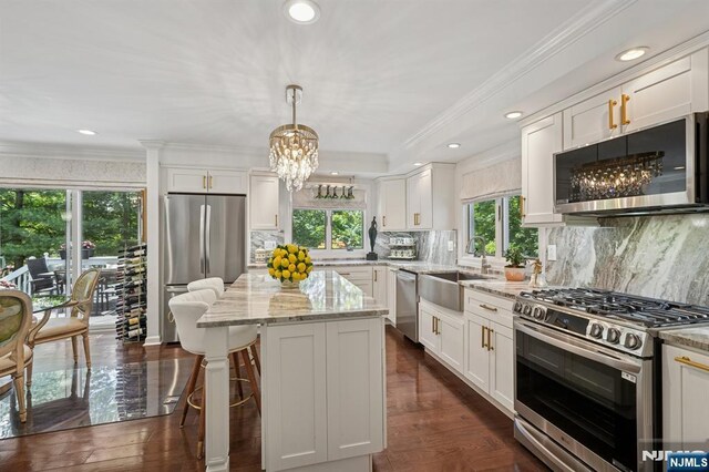15 Barberry Way, Essex Fells, NJ 07021 - kitchen featuring appliances with stainless steel finishes, ornamental molding, white cabinets, light stone countertops, and a kitchen island