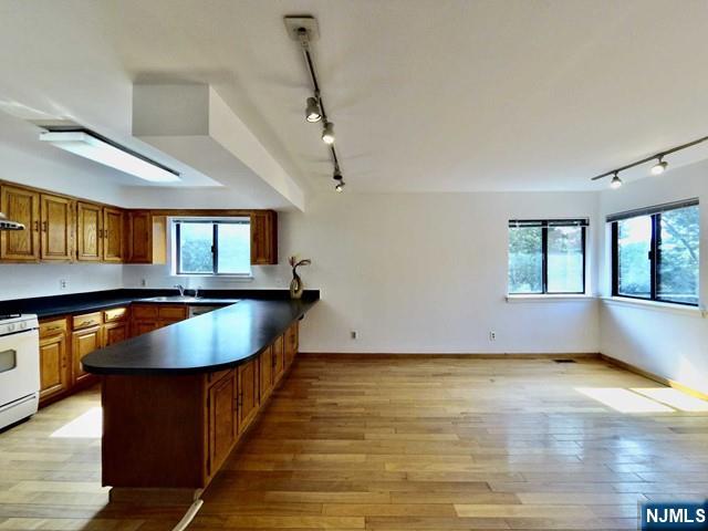 380 Whimbrel Ln Unit 380, Secaucus, NJ 07094 - kitchen with track lighting, dark countertops, a peninsula, and white range with gas stovetop