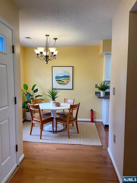 214 Manahan Rd Unit 214, East Brunswick, NJ 08816 - dining room featuring wood finished floors, a chandelier, and a textured ceiling