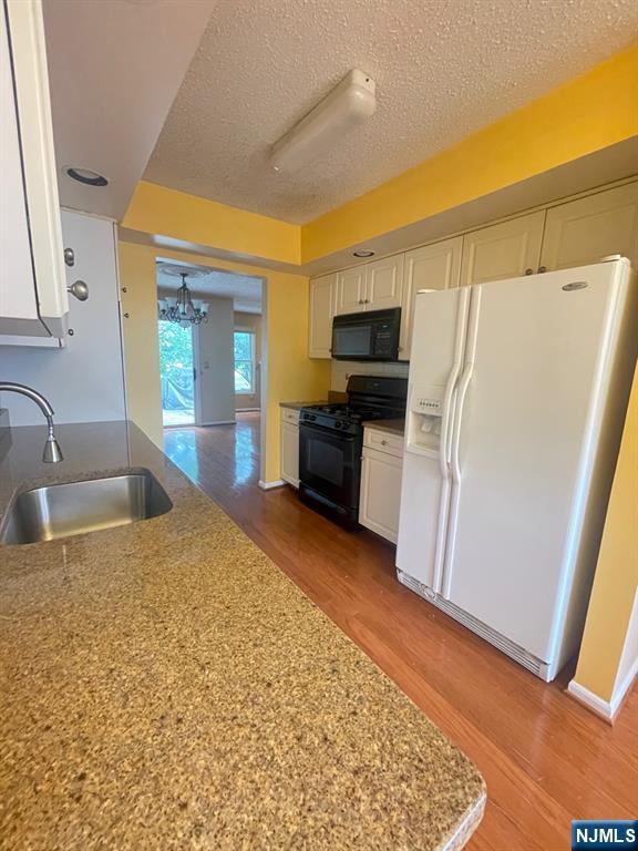 214 Manahan Rd Unit 214, East Brunswick, NJ 08816 - kitchen with black appliances, white cabinets, a textured ceiling, wood finished floors, and a chandelier