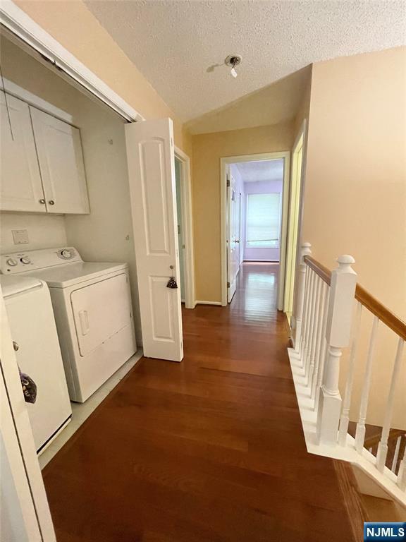 214 Manahan Rd Unit 214, East Brunswick, NJ 08816 - laundry area featuring cabinet space, washer and clothes dryer, dark wood finished floors, and a textured ceiling