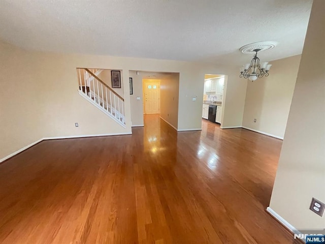 214 Manahan Rd Unit 214, East Brunswick, NJ 08816 - unfurnished living room featuring a chandelier, wood finished floors, stairway, and a textured ceiling