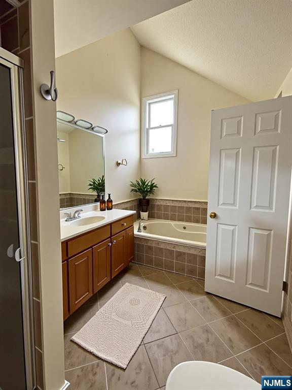 214 Manahan Rd Unit 214, East Brunswick, NJ 08816 - bathroom featuring vaulted ceiling, vanity, tile patterned flooring, a garden tub, and a stall shower