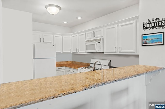 330 The Promenade, Edgewater, NJ 07020 - kitchen featuring white appliances, white cabinets, light stone countertops, recessed lighting, and a peninsula