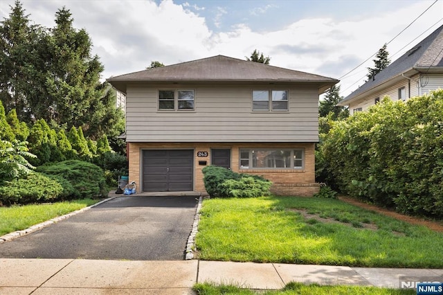 243 Lafayette Ave, Passaic, NJ 07055 - view of front facade with brick siding, a front yard, an attached garage, and driveway