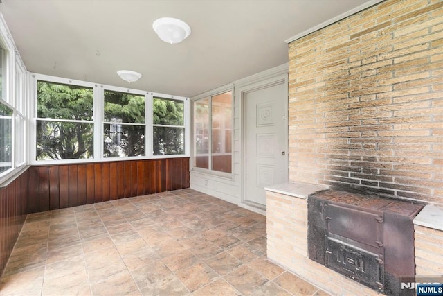 243 Lafayette Ave, Passaic, NJ 07055 - unfurnished sunroom featuring stone finish floors, wooden walls, and brick wall