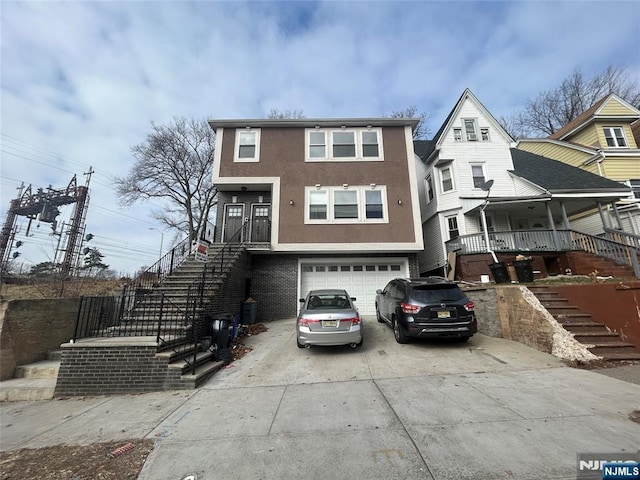 61 Grove, East Orange, NJ 07017 - townhome / multi-family property with stairs, concrete driveway, a garage, stucco siding, and covered porch