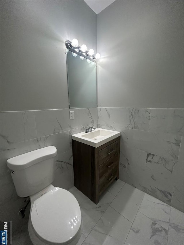 61 Grove, East Orange, NJ 07017 - half bath featuring marble look tile flooring, vanity, tile walls, and wainscoting