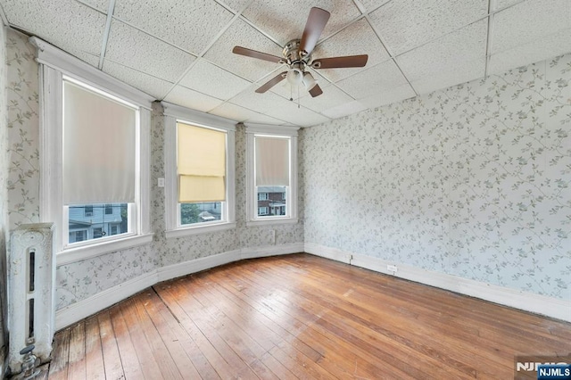 407 Elm St, Kearny, NJ 07032 - unfurnished room with wallpapered walls, wood-type flooring, a drop ceiling, and a ceiling fan