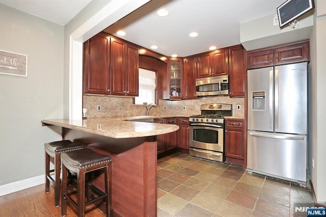 393 High St, Nutley, NJ 07110 - kitchen with appliances with stainless steel finishes, a peninsula, glass insert cabinets, backsplash, and a kitchen breakfast bar