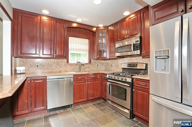 393 High St, Nutley, NJ 07110 - kitchen featuring appliances with stainless steel finishes, light stone countertops, backsplash, glass insert cabinets, and recessed lighting