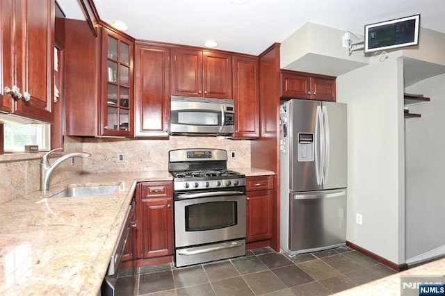 393 High St, Nutley, NJ 07110 - kitchen with appliances with stainless steel finishes, decorative backsplash, light stone counters, and glass insert cabinets