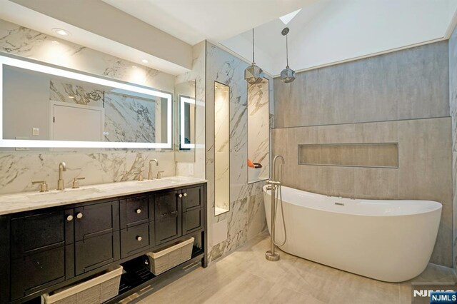 1 Columbus Pl, Cliffside Park, NJ 07010 - bathroom with tile walls, a soaking tub, double vanity, and marble finish floors