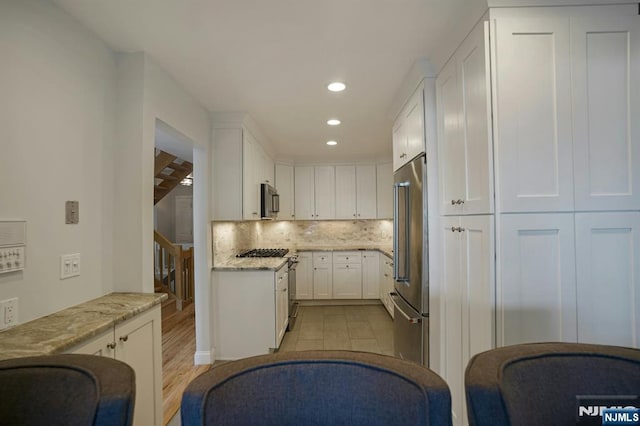 1 Columbus Pl, Cliffside Park, NJ 07010 - kitchen featuring appliances with stainless steel finishes, white cabinetry, light stone countertops, recessed lighting, and backsplash