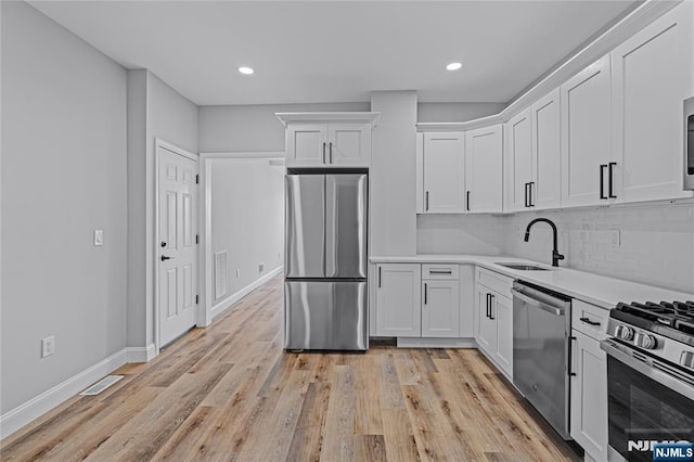 6 Pleasant Ave, Clifton, NJ 07013 - kitchen with appliances with stainless steel finishes, white cabinets, light countertops, decorative backsplash, and light wood-style flooring