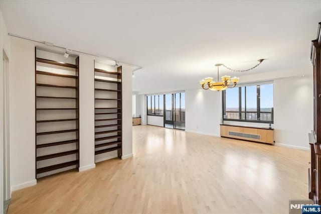 300 Winston Unit 1822, Cliffside Park, NJ 07010 - unfurnished living room featuring a chandelier, light wood-type flooring, track lighting, and radiator heating unit
