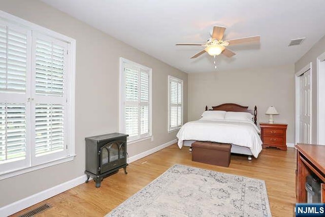 84 Pheasant Run Unit 84, Old Tappan, NJ 07675 - bedroom with multiple windows, a wood stove, light wood-type flooring, and a ceiling fan