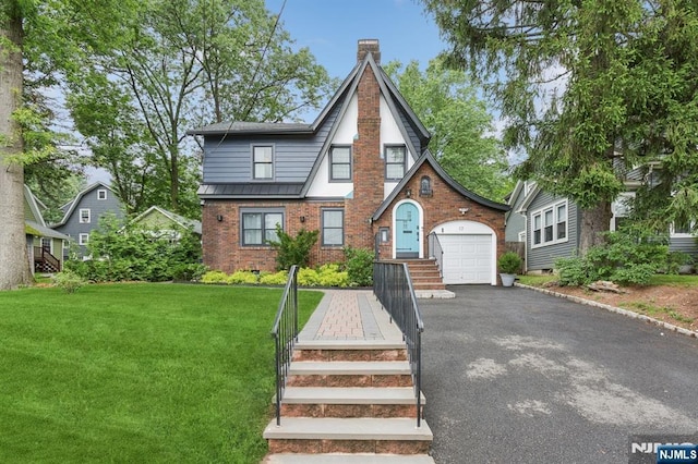 17 Lowell Ave, West Orange, NJ 07052 - tudor home featuring brick siding, driveway, a front yard, a chimney, and an attached garage