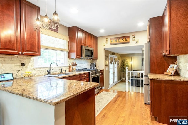 611 Maze Rd, River Vale, NJ 07675 - kitchen featuring appliances with stainless steel finishes, light wood finished floors, light stone countertops, tasteful backsplash, and a peninsula
