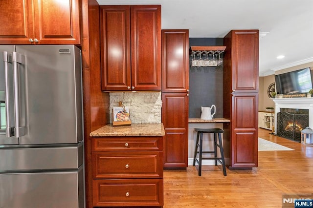 611 Maze Rd, River Vale, NJ 07675 - kitchen with high end refrigerator, crown molding, light wood-style floors, light stone counters, and a warm lit fireplace