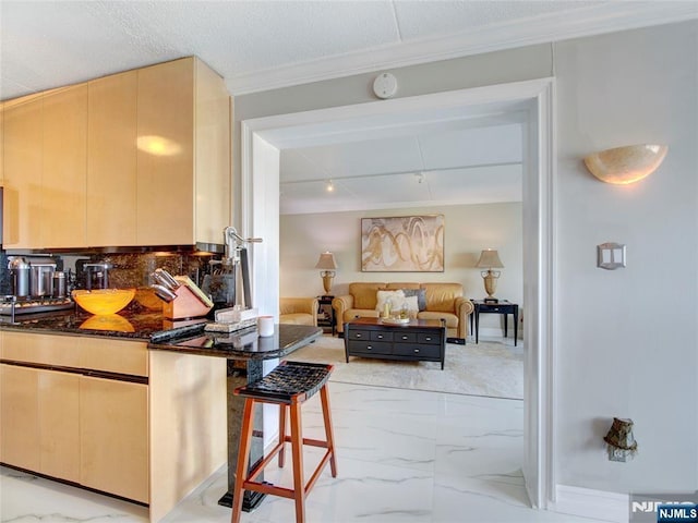 250 Gorge Rd Unit 23I, Cliffside Park, NJ 07010 - kitchen featuring light marble finish floors, dark stone countertops, a kitchen breakfast bar, crown molding, and light brown cabinets