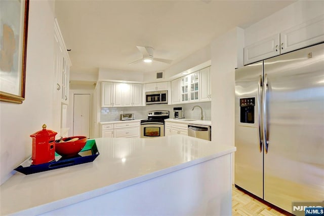 1265 15th St Unit 4C, Fort Lee, NJ 07024 - kitchen featuring stainless steel appliances, a peninsula, glass insert cabinets, backsplash, and white cabinetry