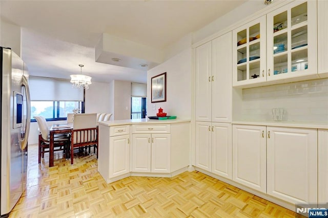 1265 15th St Unit 4C, Fort Lee, NJ 07024 - kitchen with stainless steel fridge with ice dispenser, a peninsula, light countertops, a chandelier, and white cabinets