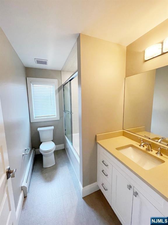 104 Sunset Pl Unit A, Palisades Park, NJ 07650 - full bathroom featuring a baseboard heating unit, vanity, and bath / shower combo with glass door
