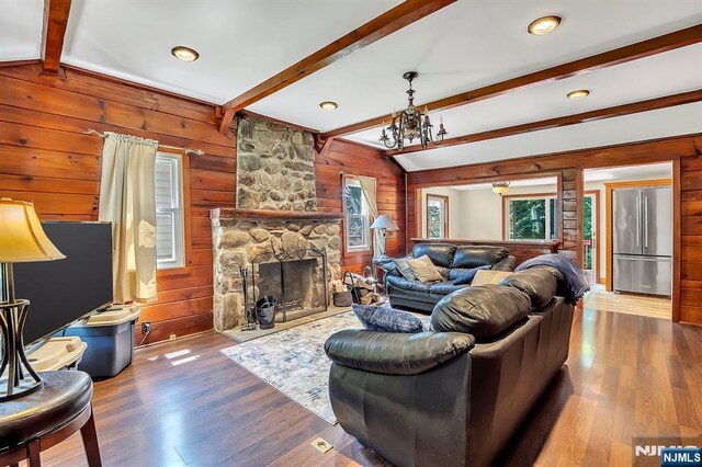 76 Hillside Rd, Sparta, NJ 07871 - living room with wood walls, wood finished floors, a fireplace, and a chandelier