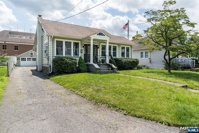 5 Rhinesmith Ave, Wanaque, NJ 07465 - bungalow-style house featuring a front yard, an outdoor structure, a detached garage, and a shingled roof